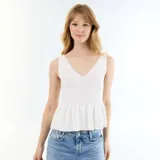 Top de canalé blanco sin mangas con escote en V y diseño peplum en la cintura.