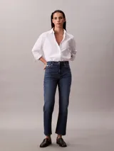 Camisa blanca de algodón y elastano, con cuello clásico de punta, cierre frontal con botones y mangas largas con puños abotonados.