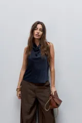 Top negro de cuello drapeado con espalda descubierta y calce fluido.