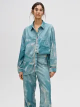 Pantalón de tiro alto con corte recto y holgado, confeccionado en tela liviana con estampado tipo tie-dye en tonos azul y blanco.