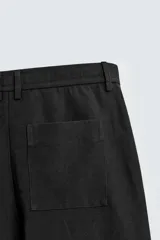 Pantalón de corte recto y ajuste relajado, confeccionado en una mezcla de algodón y lino. Presenta cintura elástica, bolsillos delanteros, bolsillo trasero de plastrón y cierre frontal con cremallera y botón.