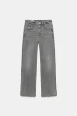 Jeans de tiro alto color gris desgastado, con corte cropped flare y bajo deshilachado. Presenta cinco bolsillos y cierre frontal con cremallera y botón metálico.