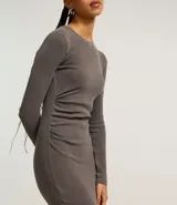 Vestido midi gris confeccionado en rib de algodón y elastano. Posee cuello redondo, manga larga y drapeado lateral con abertura en la parte inferior.