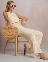 Top crop de tejido calado color beige, con escote redondo, sin mangas y aberturas laterales ajustables con lazos.