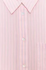 Camisa oversize de cuello solapa, manga larga con hombro caído y puños. Presenta un bolsillo de plastrón en el delantero y cierre frontal con botones.