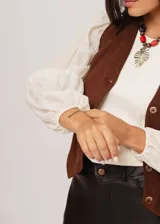 Blusa color manteca de cuello redondo y mangas largas abullonadas con puños elásticos.