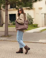 Botas cortas de cuero color caoba, con suela track negra, cierre lateral y correas con hebillas metálicas decorativas.