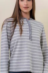 Remera de manga larga con diseño de rayas horizontales verdes sobre fondo crudo, cuello redondo con detalle de volado y cartera frontal con botones.