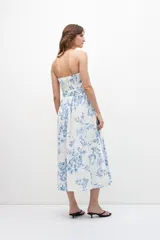 Vestido midi strapless con estampa floral azul sobre fondo blanco, con cinturón.