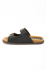 Sandalias de cuero negro con diseño de doble tira con hebillas metálicas doradas, plantilla de corcho y suela plana marrón.