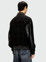 Campera estilo bomber Diesel modelo L-Nyn, color negro, con cuerpo de cuero texturizado y mangas de cuero liso, cierre frontal con broches a presión y cuello, puños y dobladillo de punto elástico rayado.