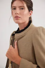 Tapado de lana color tostado con cuello mao y detalles de pana negra en el cuello y bordes frontales. Presenta mangas con hombreras y diseño estructurado.