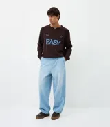 Pantalón de jean corte baggy, de tiro alto y pierna ancha, con diseño de cinco bolsillos, trabillas para cinturón y cierre frontal con botón y cremallera.
