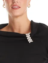 Buzo de tejido de punto color negro, con cuello volcado y detalle de aplique de perlas en el lateral. Posee mangas largas y corte ajustado.