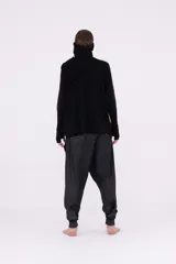 Sweater negro de tejido de punto, con cuello tortuga que se puede usar como pasamontañas, mangas largas con abertura para el dedo y roturas verticales en el frente.