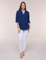 Blusa verde de calce holgado y caída fluida, confeccionada en tejido tipo crepé. Cuenta con cuello camisero con solapa, escote en V y cierre parcial al frente con tres botones metálicos. Las mangas son largas con puños abotonados.