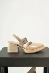 Zapato de tacón cuadrado y plataforma, color beige, con punta cerrada y tira ajustable con hebilla metálica en el tobillo.
