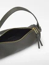Bolso cilíndrico pequeño de textura granulada, con cierre de cremallera superior, asa de hombro fija y correa larga regulable extraíble. Presenta el logo de la marca grabado en el frente.