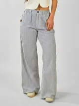 Pantalón ancho recto a rayas verticales azules y blancas, confeccionado en tela Oxford. Tiene pretina con cierre y elástico en la parte trasera.