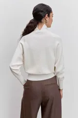 Sweater de punto color negro, con cuello alto y mangas largas de corte raglán.