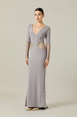 Vestido largo color gris con escote en V, mangas largas y aberturas laterales con tejido de red metálica que se extiende desde la cintura hasta los antebrazos.