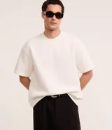 Remera de corte boxy con cuello redondo y mangas cortas, confeccionada en tejido de malla pesada con textura gomosa.