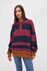 Buzo de punto con diseño de rayas horizontales en tonos bordó, azul marino y mostaza. Presenta cuello tipo polo con cartera de botones, mangas largas y calce holgado.