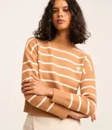 Suéter de punto pesado color tostado con rayas blancas horizontales, cuello alto y sisa caída. Presenta un pequeño corazón bordado en el pecho y acabados acanalados en cuello, puños y bajo.