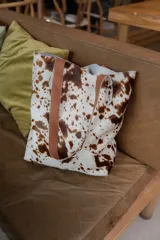 Bolso tipo tote de cuero con pelo color marrón y blanco, con manijas de cuero crudo.