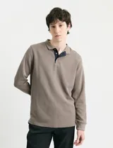 Remera de manga larga con cuello polo, confeccionada en tejido de punto canalé francés. Presenta abotonadura frontal con botones de madera y detalles a contratono en la cartera y el interior del cuello.