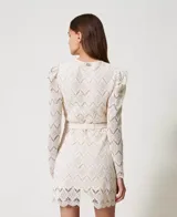 Vestido corto color blanco de encaje macramé con diseño geométrico, escote de pico, mangas largas abullonadas tipo guante con cremallera invisible en el bajo, cierre de cremallera en el lateral, bajo festoneado, forro de muselina de algodón y cinturón extraíble a juego con elástico y hebilla con el logotipo Oval T dorado, de corte recto.