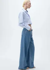 Pantalón wide leg de tiro medio, confeccionado en tejido mezcla de algodón y lino. Presenta cintura con elástico, cierre frontal, trabillas y cinturón ajustable tipo lazo. Cuenta con diseño de cinco bolsillos.
