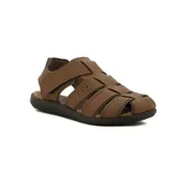 Sandalia cerrada tipo pescador para hombre, color marrón, con tiras entrelazadas y cierre de velcro en el empeine. Posee suela de goma oscura.