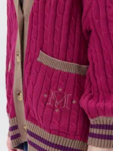 Cardigan oversize de punto color fucsia, con diseño trenzado, cuello en V y detalles en marrón y violeta en la botonera, bolsillos delanteros, puños y ruedo.