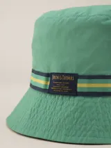 Gorro tipo bucket verde con cinta decorativa azul y amarilla.