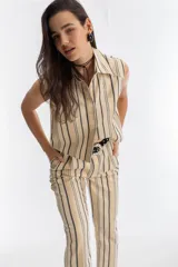 Top sin mangas confeccionado en jacquard de algodón con rayas doradas, negras y crudas. Presenta cuello clásico y cartera de botones oculta.