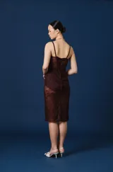 Vestido midi de encaje color marrón chocolate, con diseño tipo corset en el torso y breteles finos. Presenta transparencias en la falda y detalles de encaje en el escote.