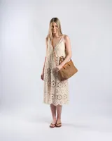 Cartera tipo tote bag color habano, combinando cuerpo de tejido texturizado tipo red y detalles en cuero sintético con costuras en contraste. Cuenta con doble asa corta de mano y correa larga ajustable y desmontable. Incluye aplique metálico con el logo de la marca en el frente.