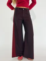 Pantalón de denim gris oscuro con paneles laterales en color bordó y corte acampanado.