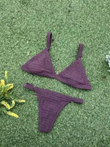 Conjunto de bikini color bordó de tejido fruncido, compuesto por un corpiño de triángulo fijo con tirantes anchos y una bombacha colaless regulable con argollas doradas en los laterales.