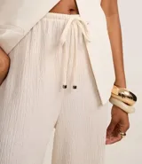Pantalón wide leg color crudo, con cintura elástica ajustable con cordón y textura.
