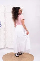 Pollera larga blanca de tiro alto, con cintura elástica y diseño amplio de volados escalonados.
