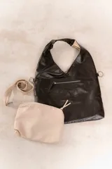 Bolso tipo tote negro de cuero sintético con correa de hombro ajustable y extraíble. Incluye un monedero beige con cierre.