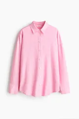 Camisa de corte oversized en tejido liviano de lino y viscosa, de color rosado. Cuenta con cuello clásico, cierre frontal de botones, hombros caídos y mangas largas con puños abotonados. El diseño se completa con un bajo redondeado.