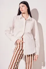 Camisa blanca oversize de algodón, con cuello clásico, cierre frontal con botones de nácar y bolsillo en el pecho.