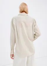 Camisa de manga larga con diseño de rayas verticales en tonos suaves, cuello clásico, cierre frontal con botones y bolsillo ojal en el pecho.