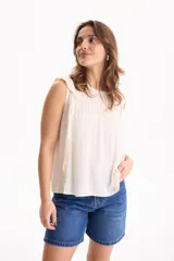 Blusa de viscosa negra sin mangas, con diseño fluido, cuello redondo y detalles de tablas verticales en el pecho con terminaciones de encaje en las sisas.