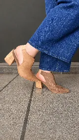 Zapatos abiertos en el talón modelo Eliana, con taco bloque de madera de 7,5 cm, punta fina y diseño lateral con abertura. Combinan diferentes texturas y tonos de cuero en color camel.