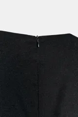 Vestido corto negro sin mangas, con cuello redondo y diseño de falda con volumen tipo globo. Presenta un corte entallado en el torso y cierre de cremallera oculta en la espalda.