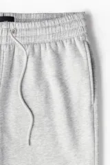 Pantalón de jogging gris de felpa liviana de mezcla de algodón con interior cepillado suave. Modelo con elástico revestido y cordón para ajustar en la cintura, bolsillos en las costuras laterales y puños acanalados.